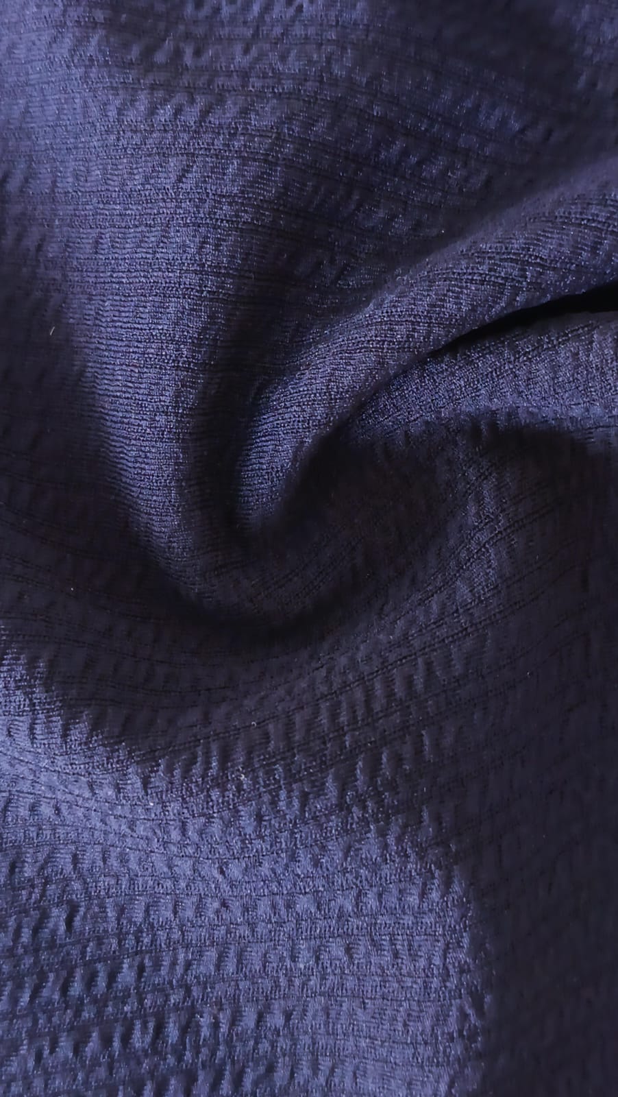 Close-up of soft, wrinkled pink cotton fabric displaying fine weave texture.