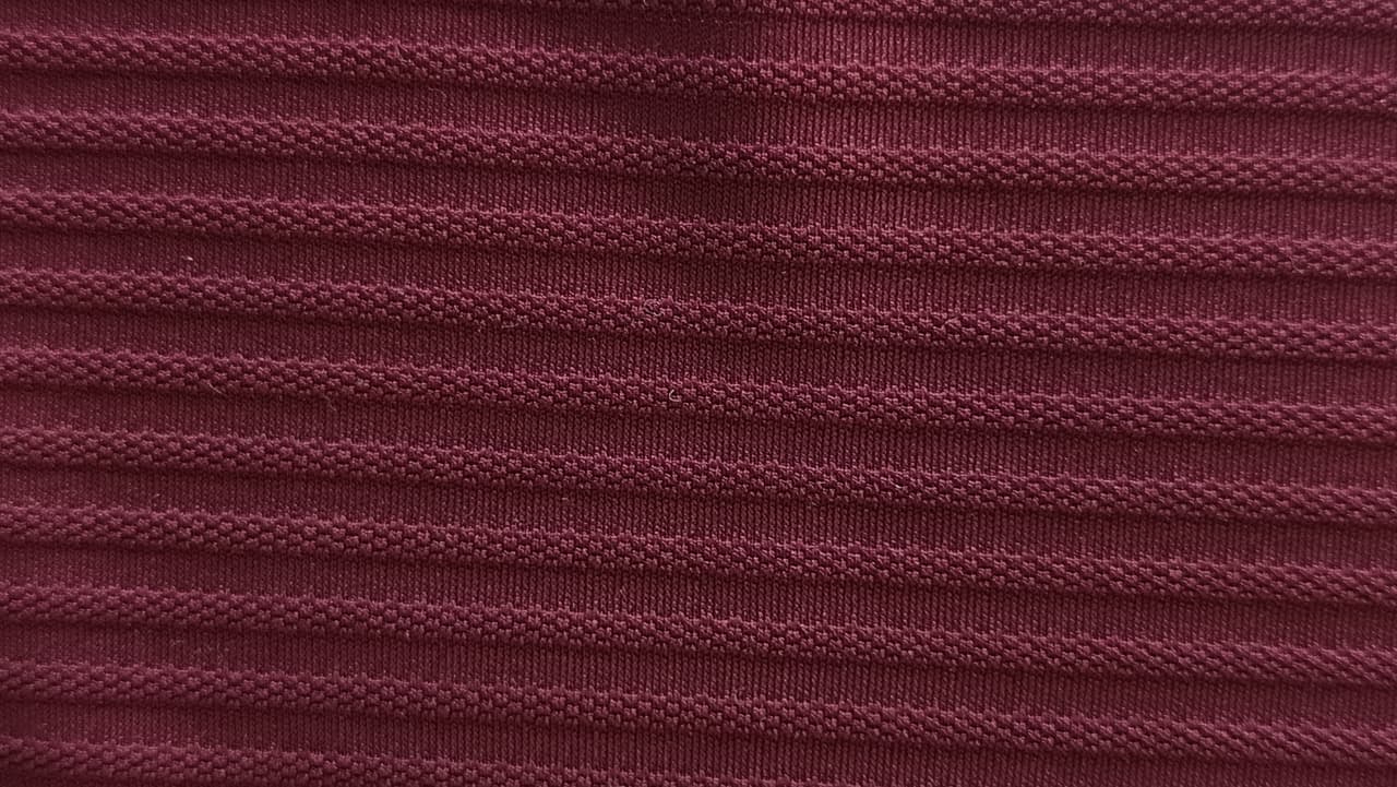 Close-up of soft, wrinkled pink cotton fabric displaying fine weave texture.