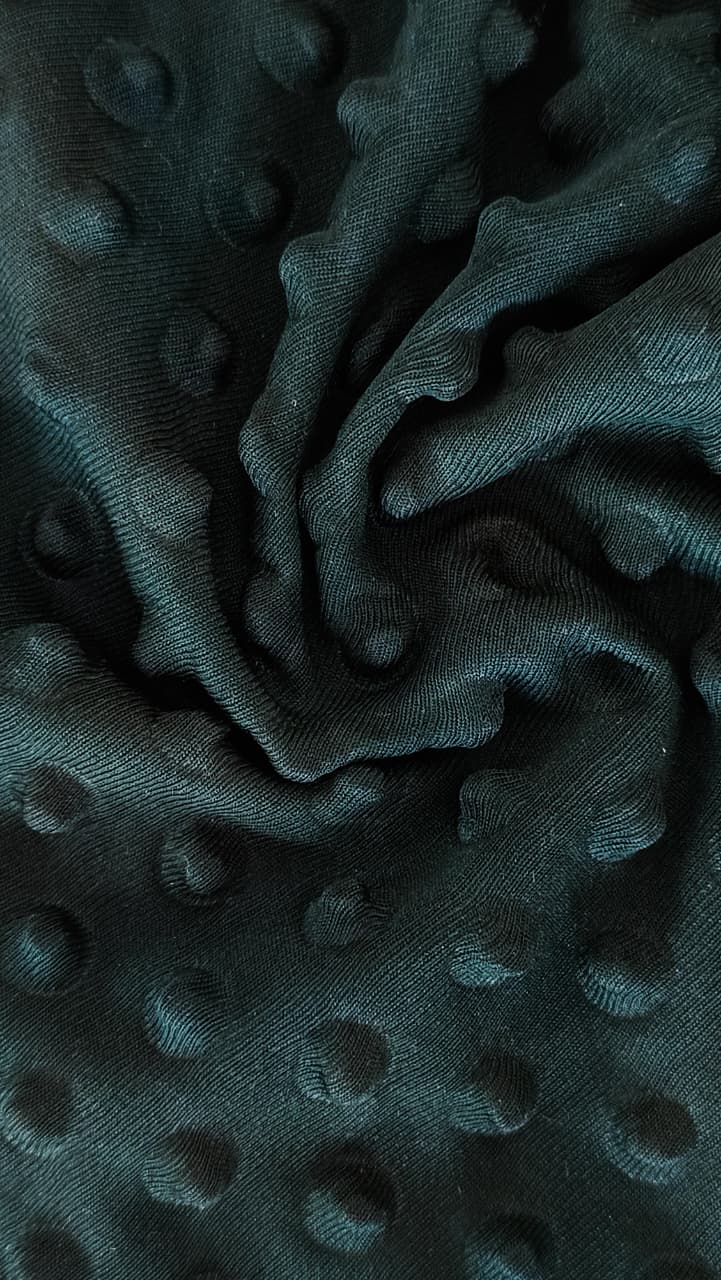 Close-up of soft, wrinkled pink cotton fabric displaying fine weave texture.