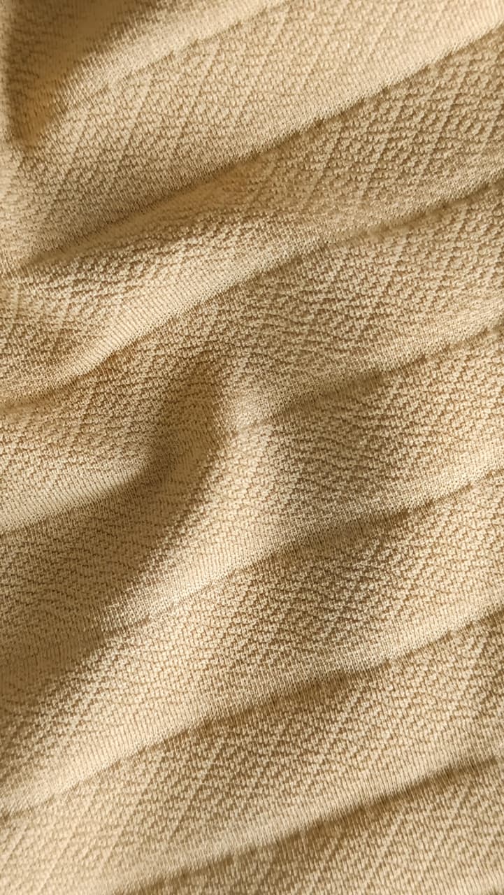 Close-up of soft, wrinkled pink cotton fabric displaying fine weave texture.