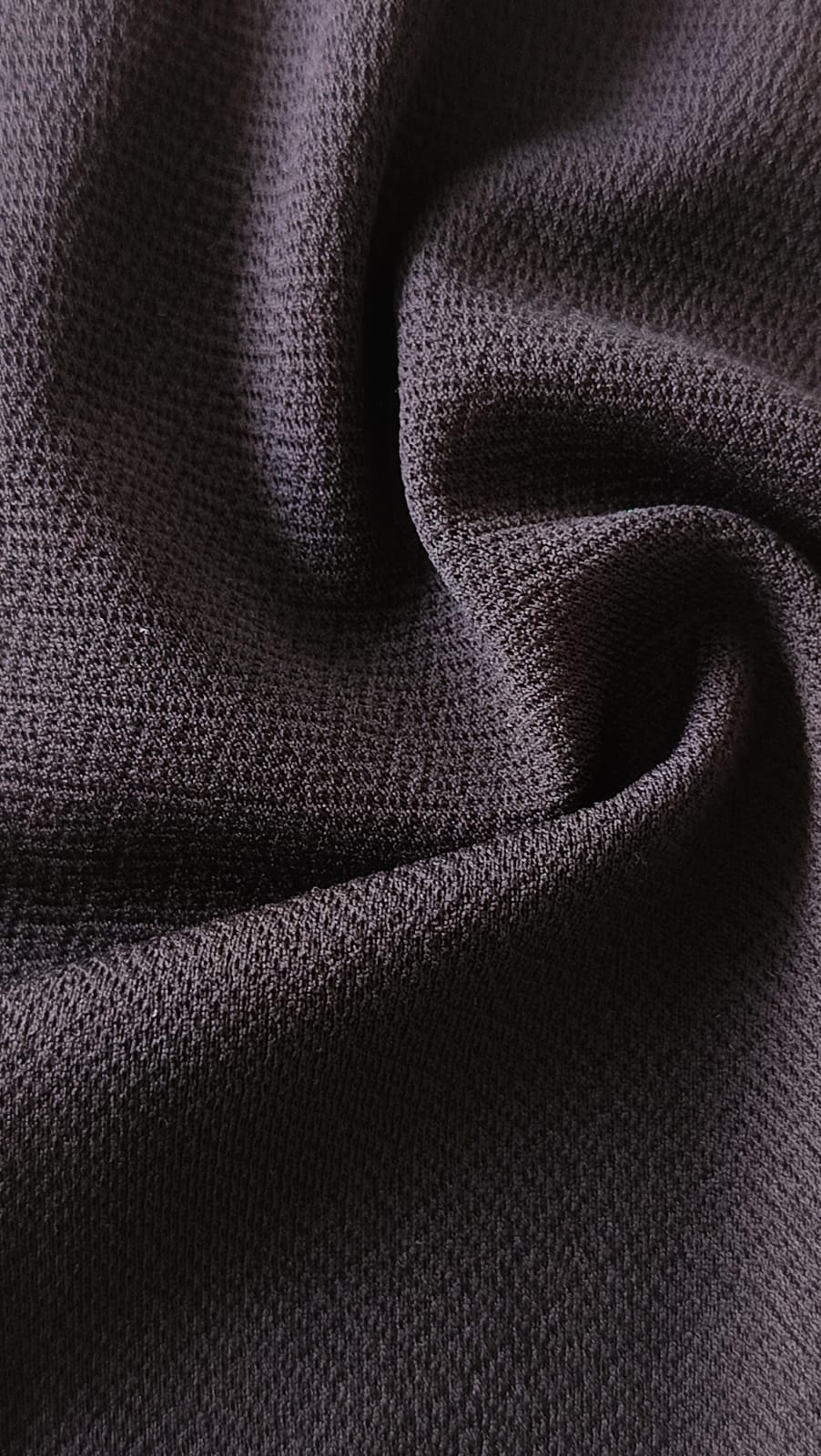 Close-up of soft, wrinkled pink cotton fabric displaying fine weave texture.