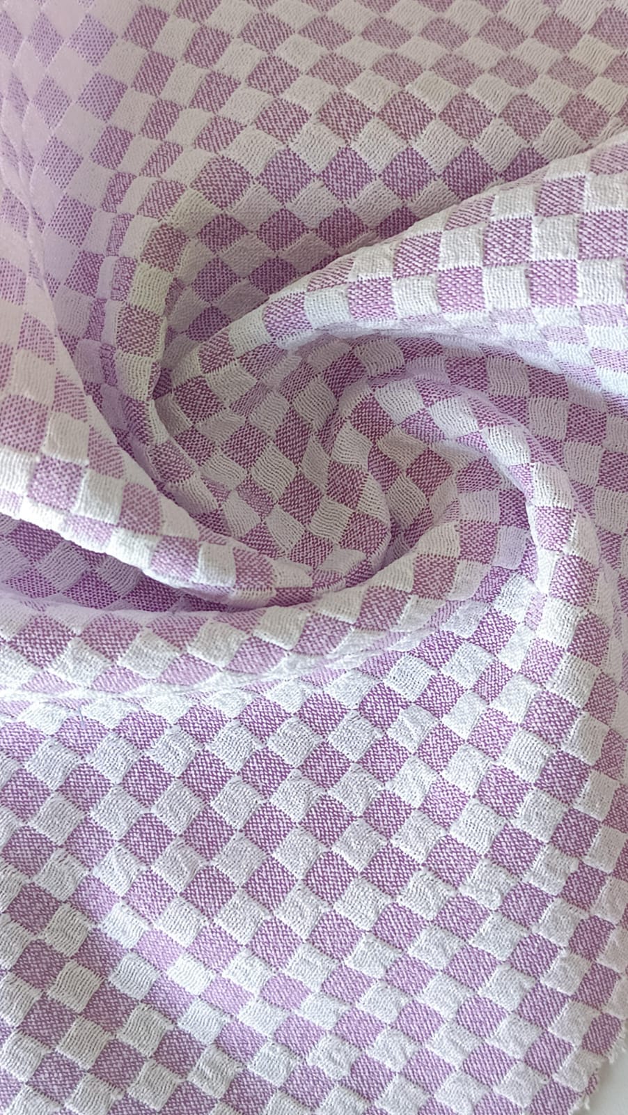 Close-up of soft, wrinkled pink cotton fabric displaying fine weave texture.