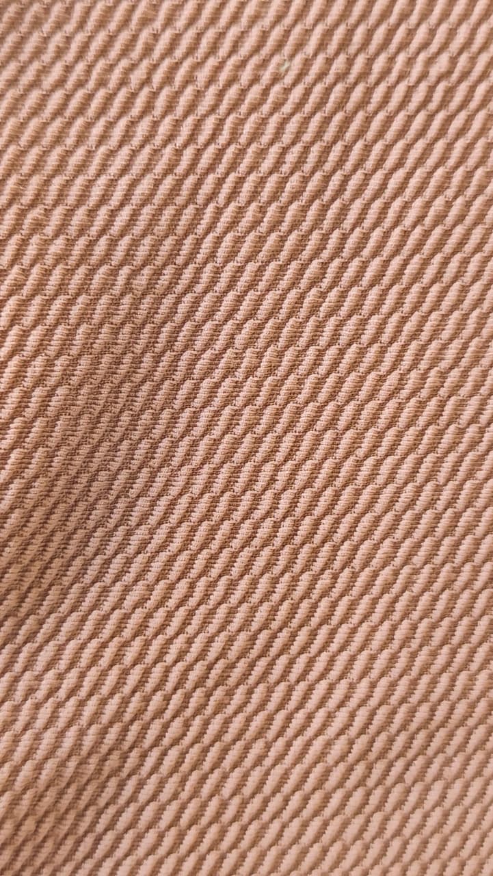 Close-up of soft, wrinkled pink cotton fabric displaying fine weave texture.