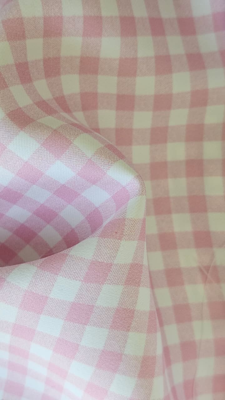 Close-up of soft, wrinkled pink cotton fabric displaying fine weave texture.