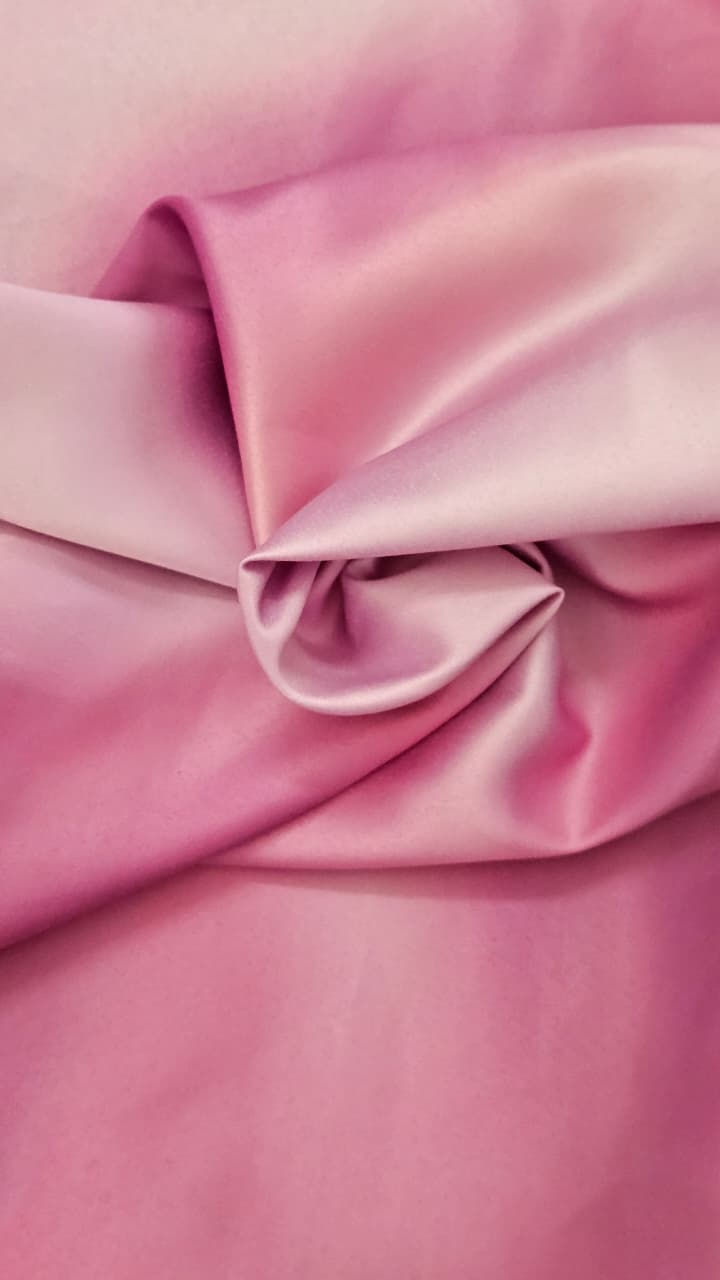 Close-up of soft, wrinkled pink cotton fabric displaying fine weave texture.
