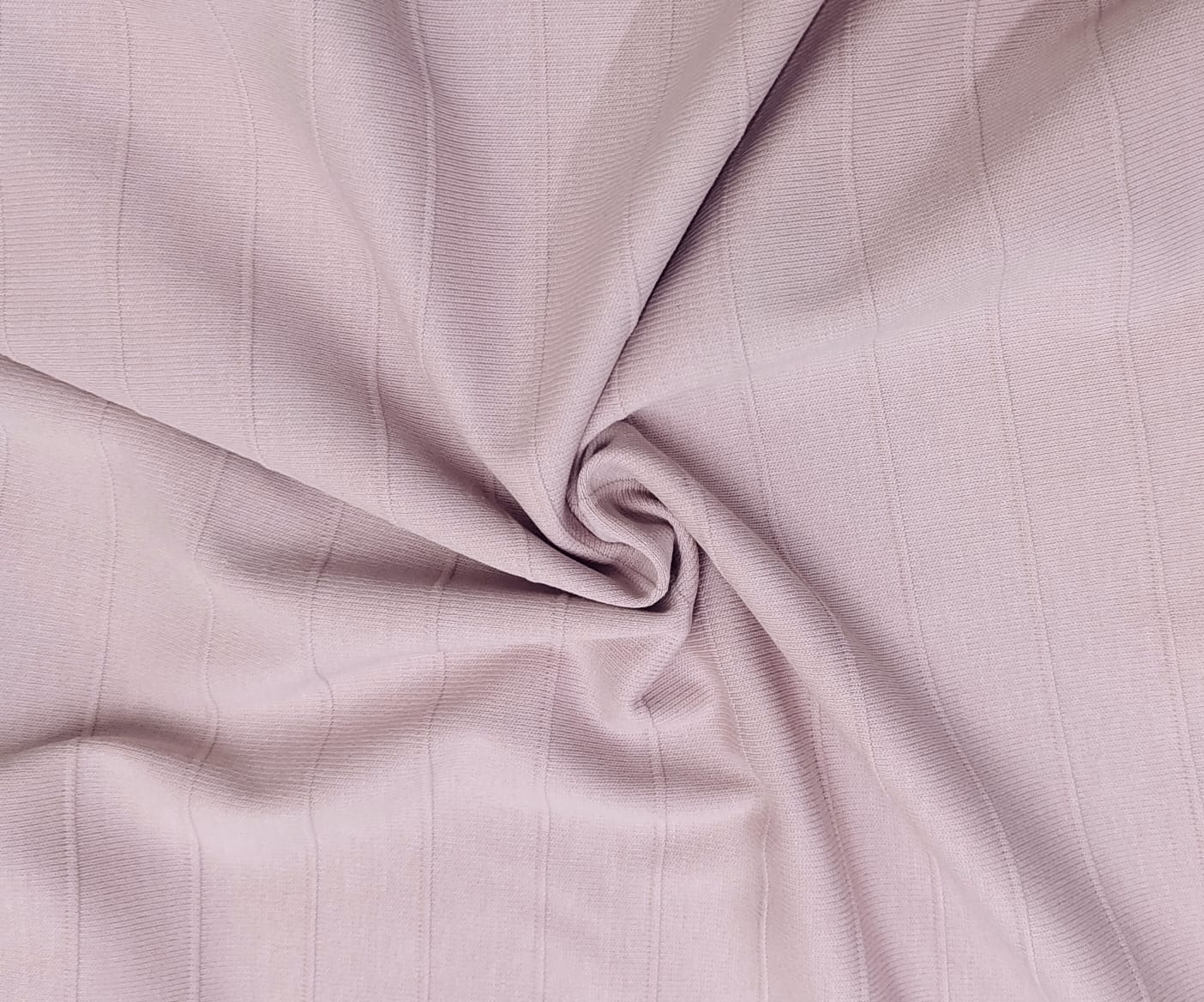 Close-up of soft, wrinkled pink cotton fabric displaying fine weave texture.