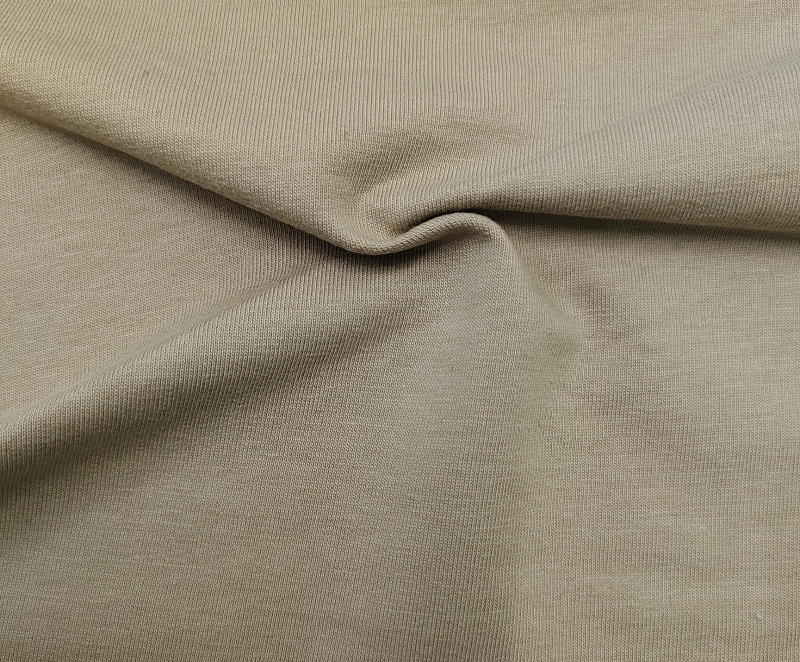 Close-up of soft, wrinkled pink cotton fabric displaying fine weave texture.