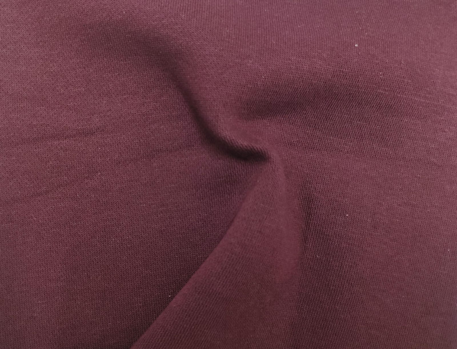 Close-up of soft, wrinkled pink cotton fabric displaying fine weave texture.