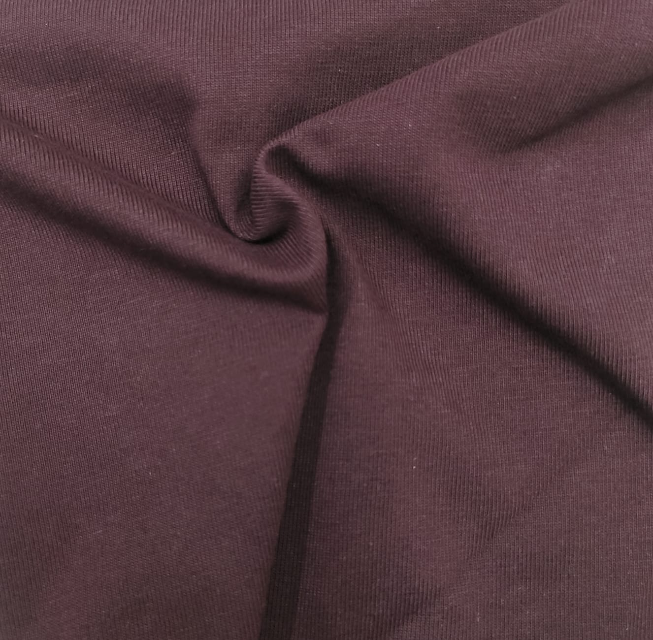 Close-up of soft, wrinkled pink cotton fabric displaying fine weave texture.