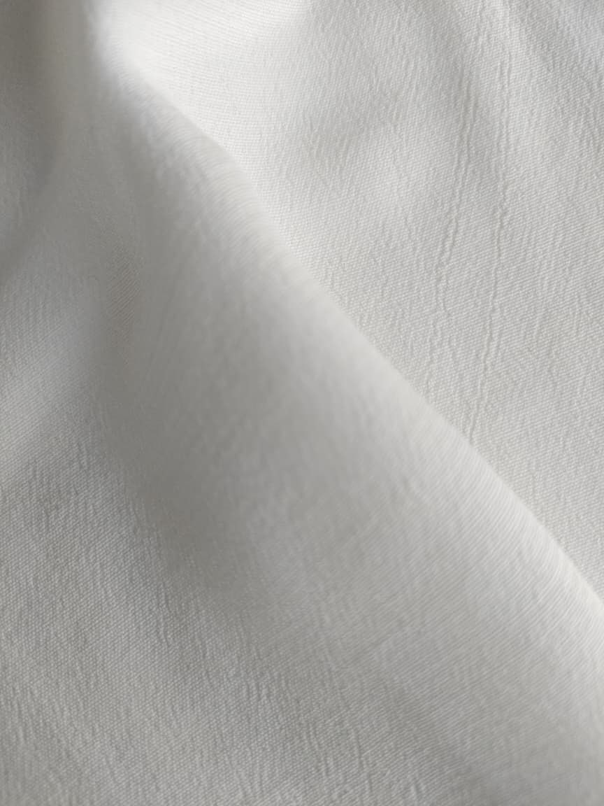 Close-up of soft, wrinkled pink cotton fabric displaying fine weave texture.