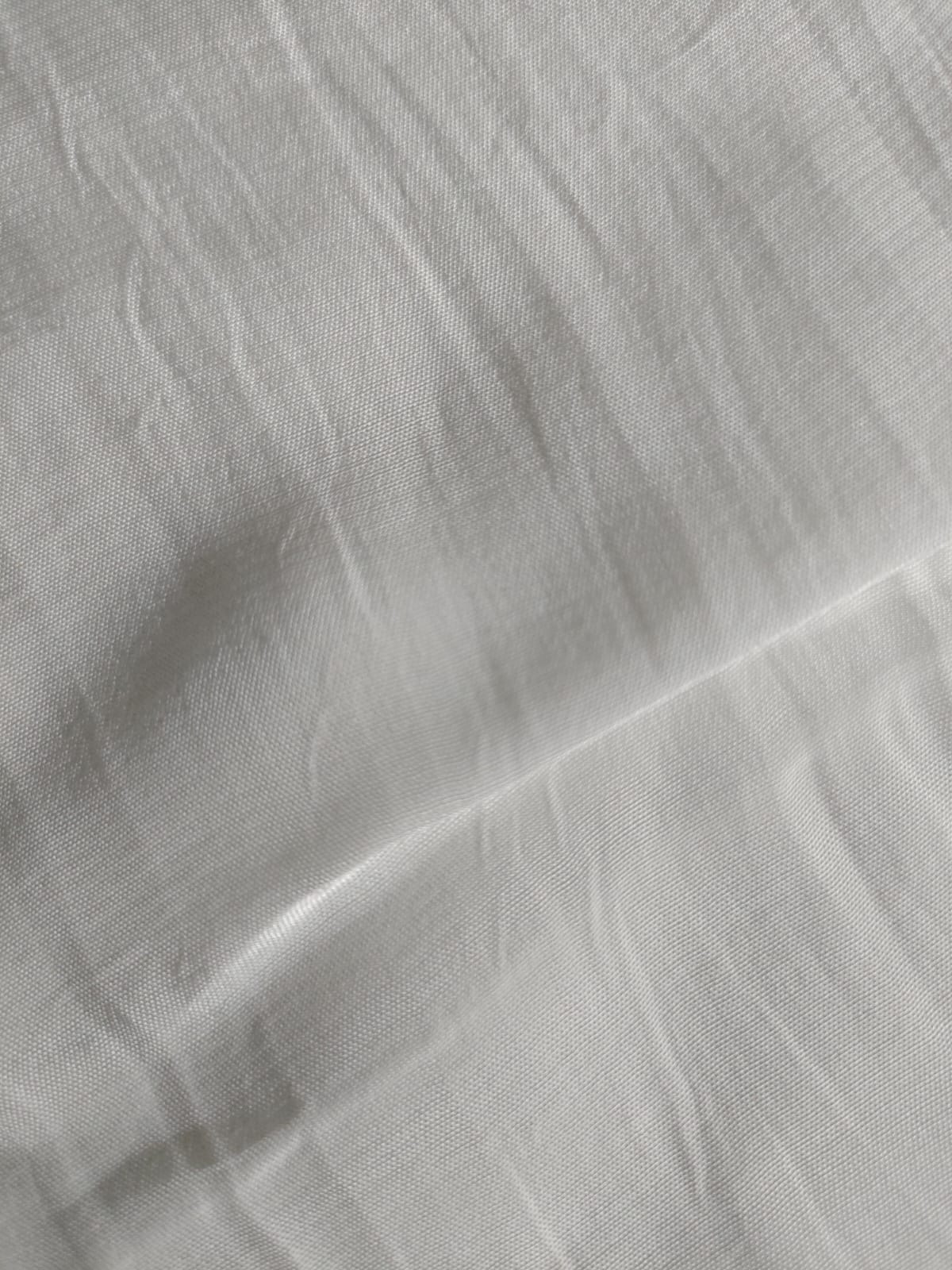 Close-up of soft, wrinkled pink cotton fabric displaying fine weave texture.