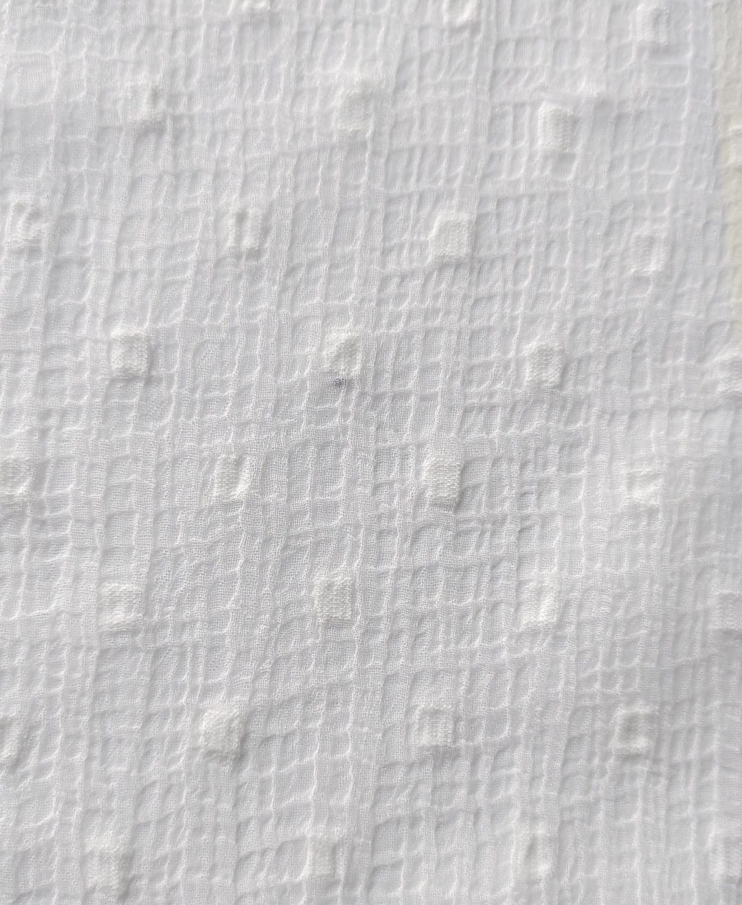 Close-up of soft, wrinkled pink cotton fabric displaying fine weave texture.