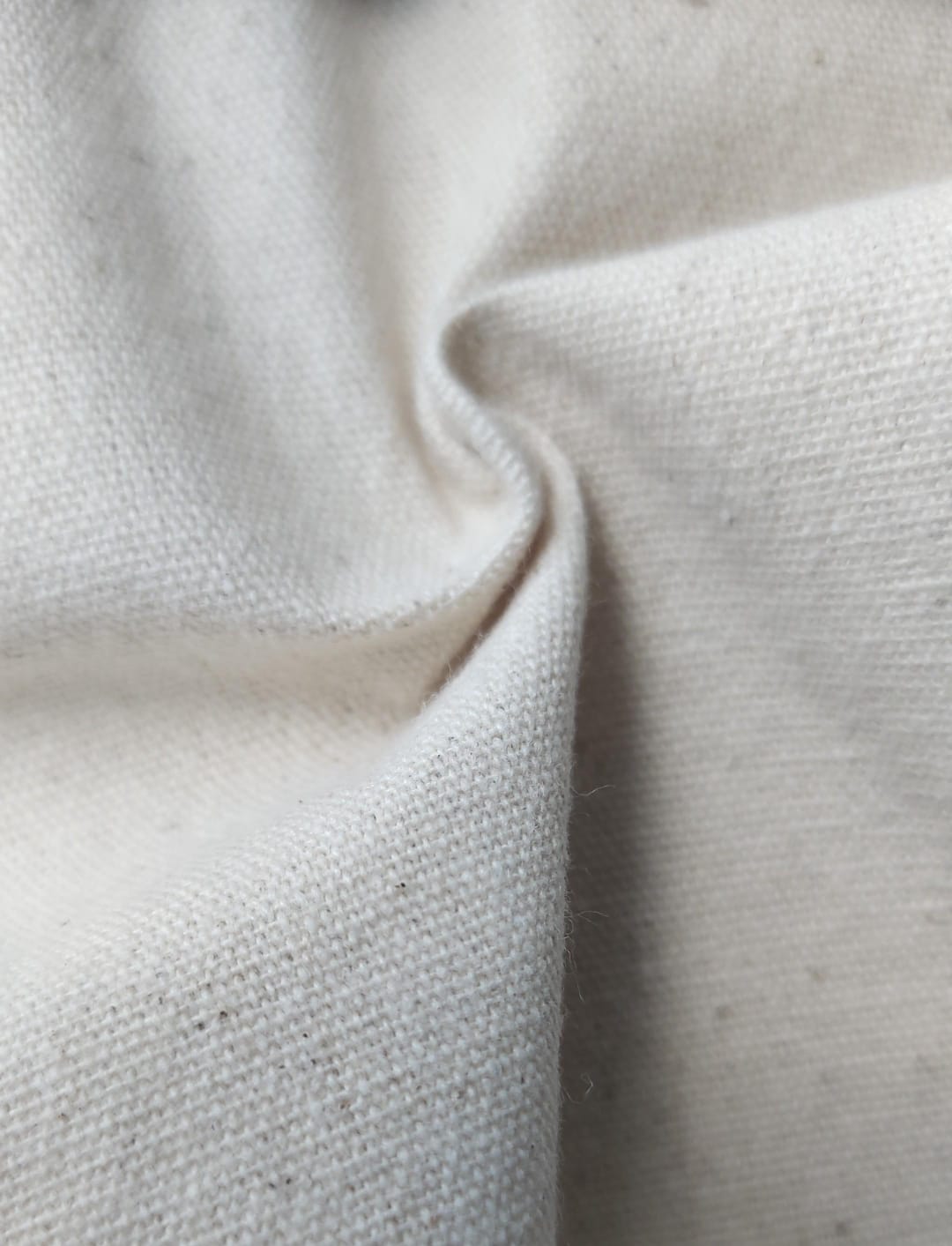 Close-up of soft, wrinkled pink cotton fabric displaying fine weave texture.