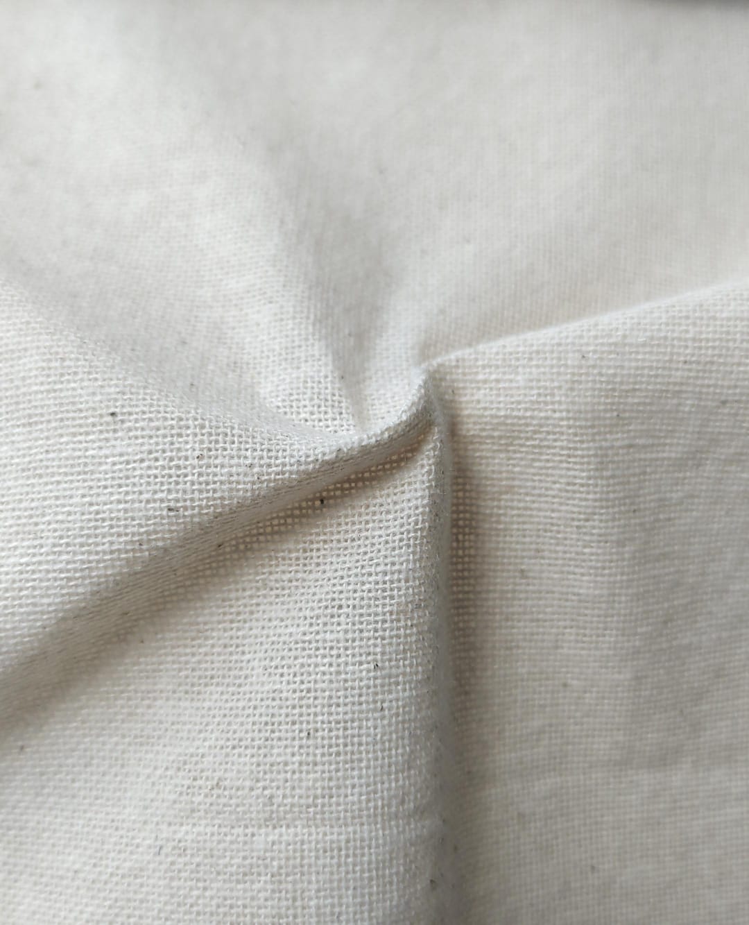 Close-up of soft, wrinkled pink cotton fabric displaying fine weave texture.