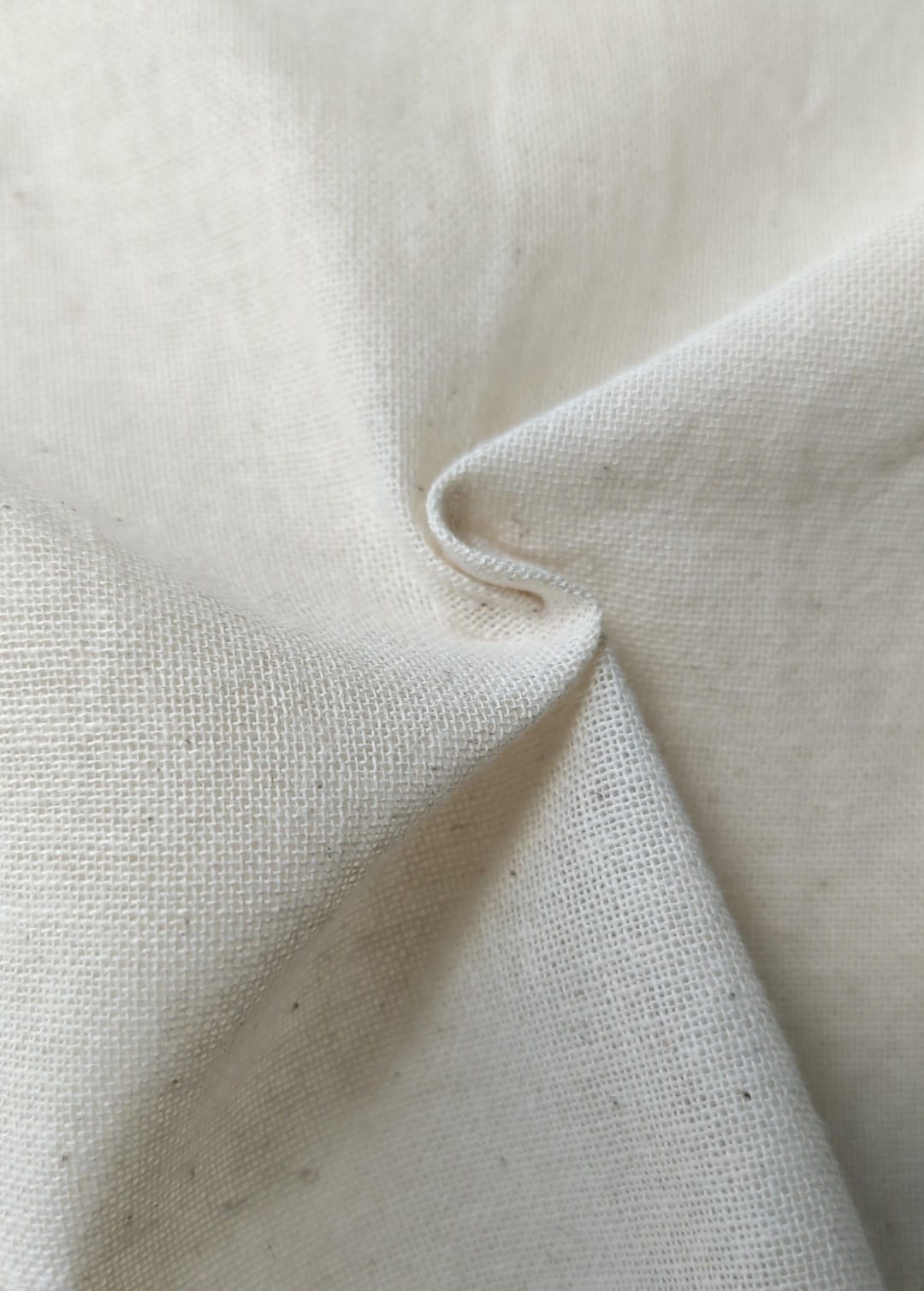 Close-up of soft, wrinkled pink cotton fabric displaying fine weave texture.