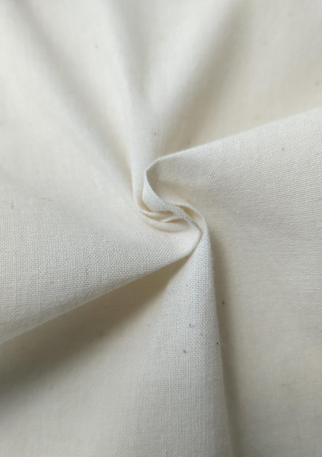 Close-up of soft, wrinkled pink cotton fabric displaying fine weave texture.