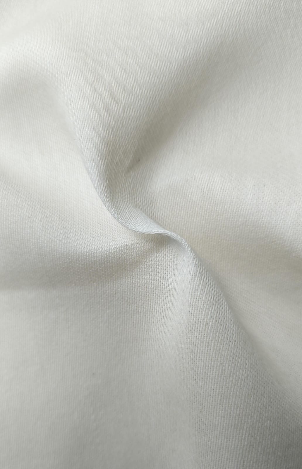 Close-up of soft, wrinkled pink cotton fabric displaying fine weave texture.