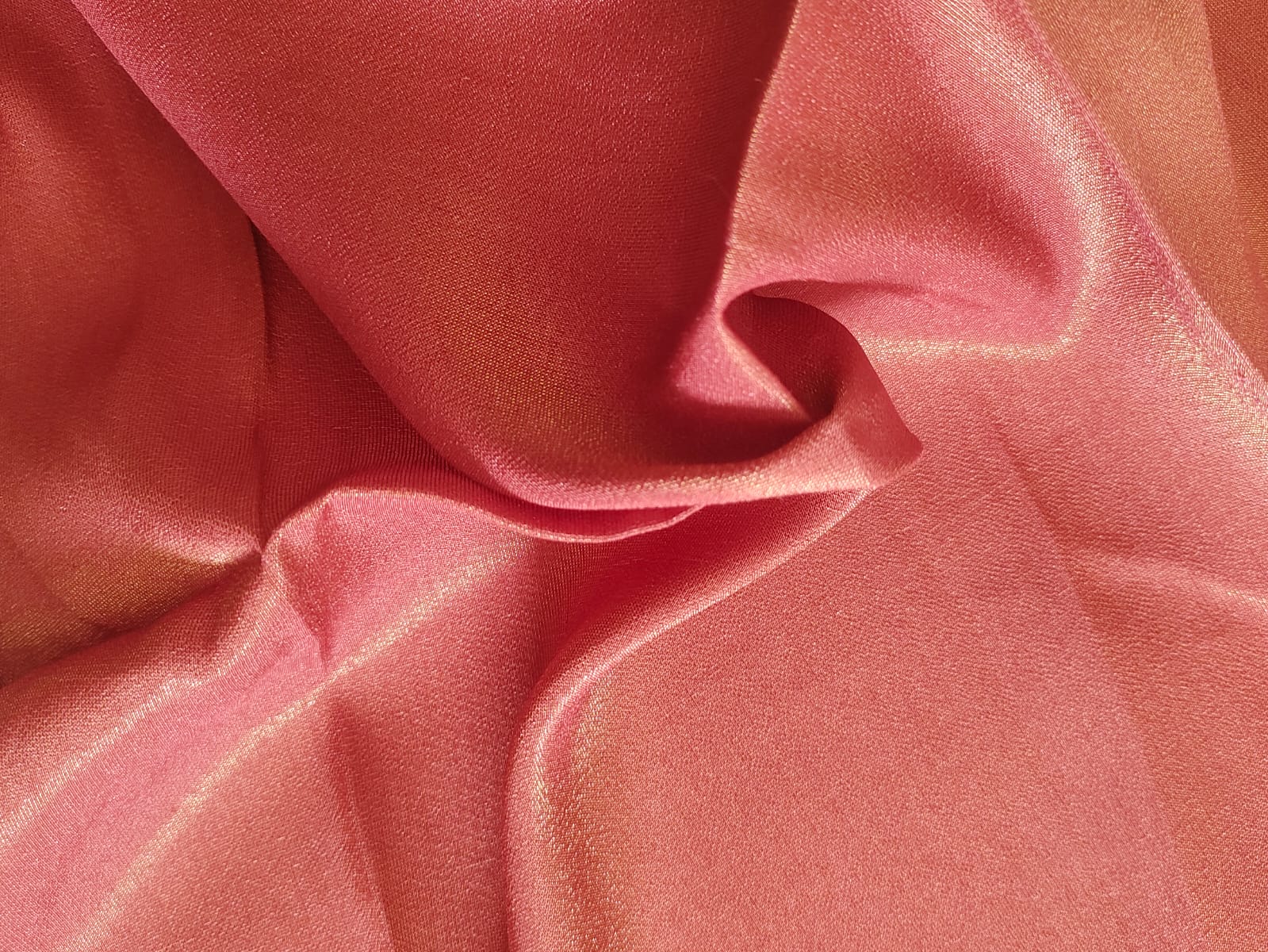 Close-up of soft, wrinkled pink cotton fabric displaying fine weave texture.