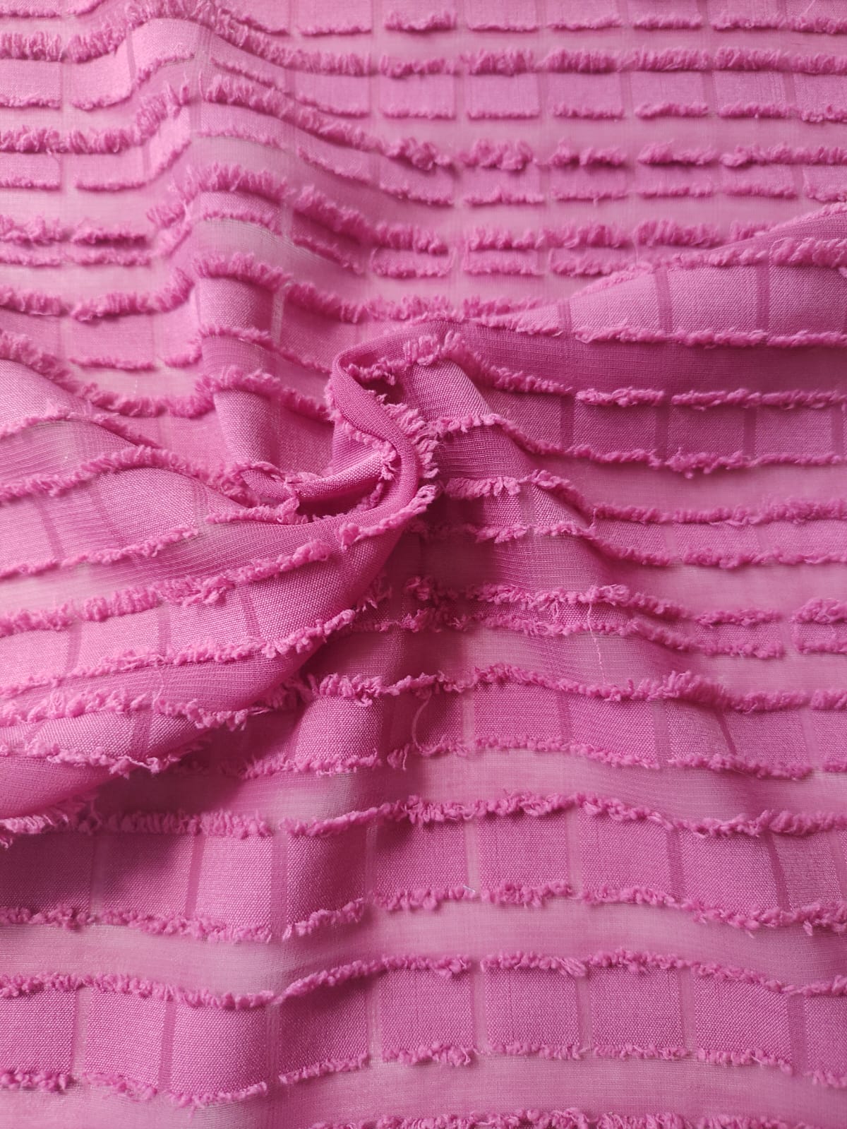 Close-up of soft, wrinkled pink cotton fabric displaying fine weave texture.