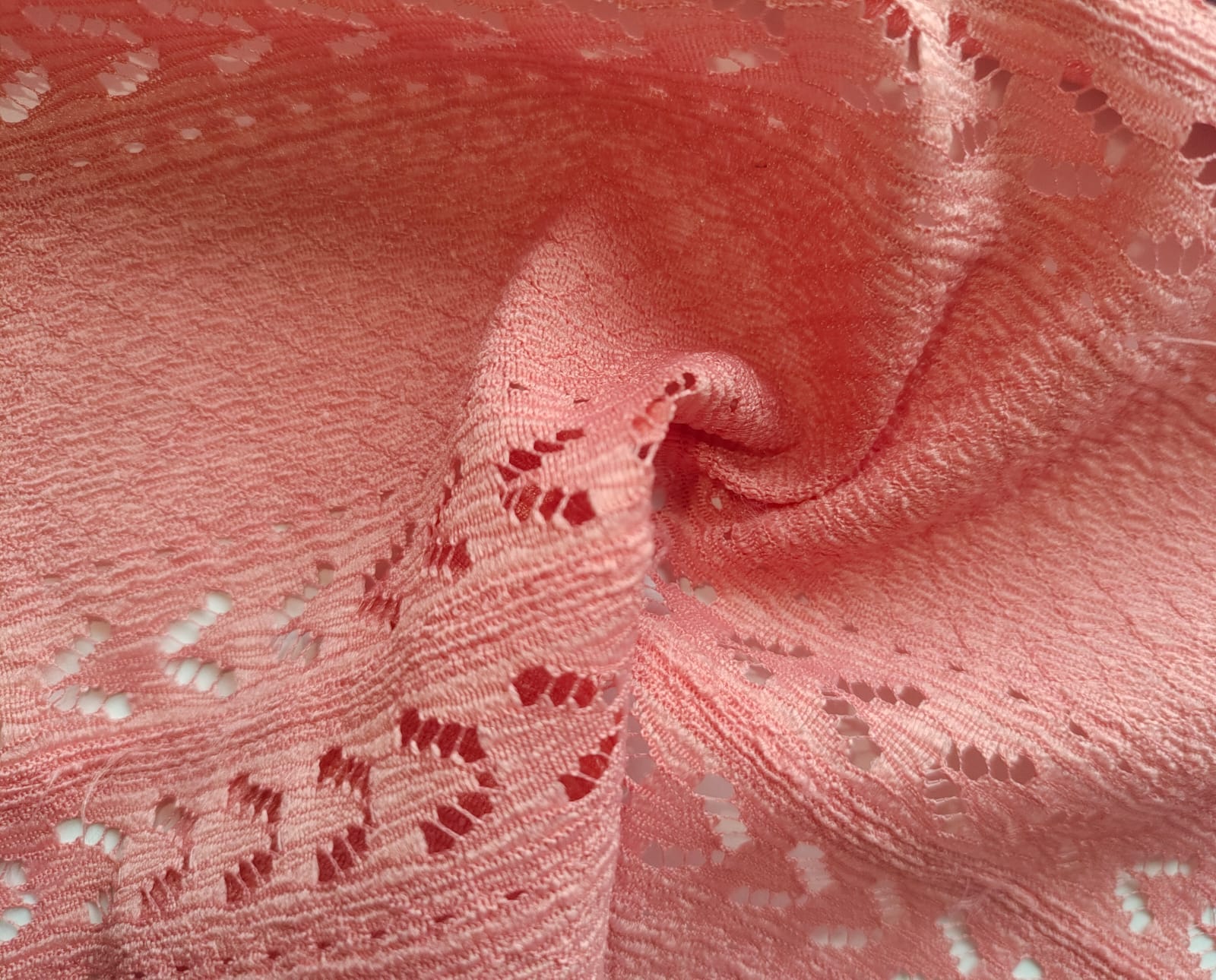 Close-up of soft, wrinkled pink cotton fabric displaying fine weave texture.