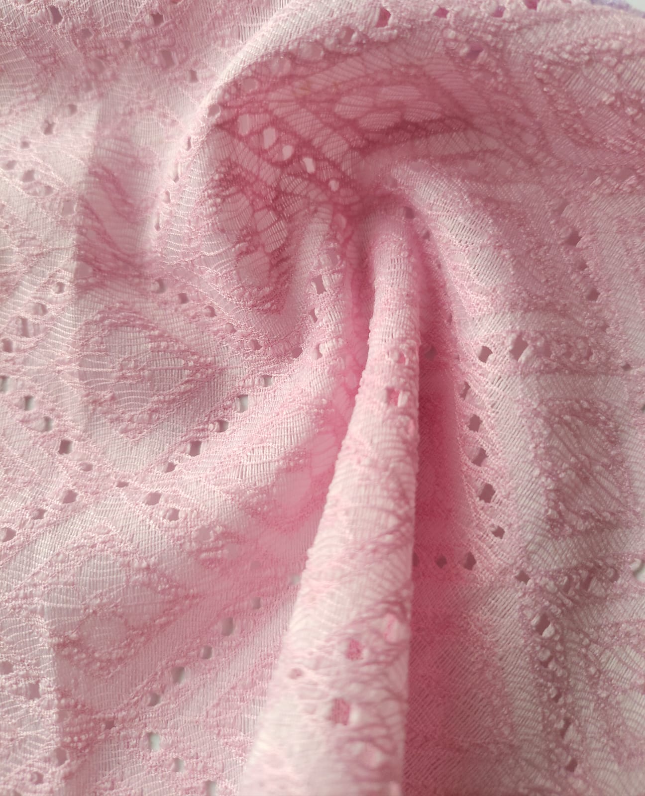 Close-up of soft, wrinkled pink cotton fabric displaying fine weave texture.