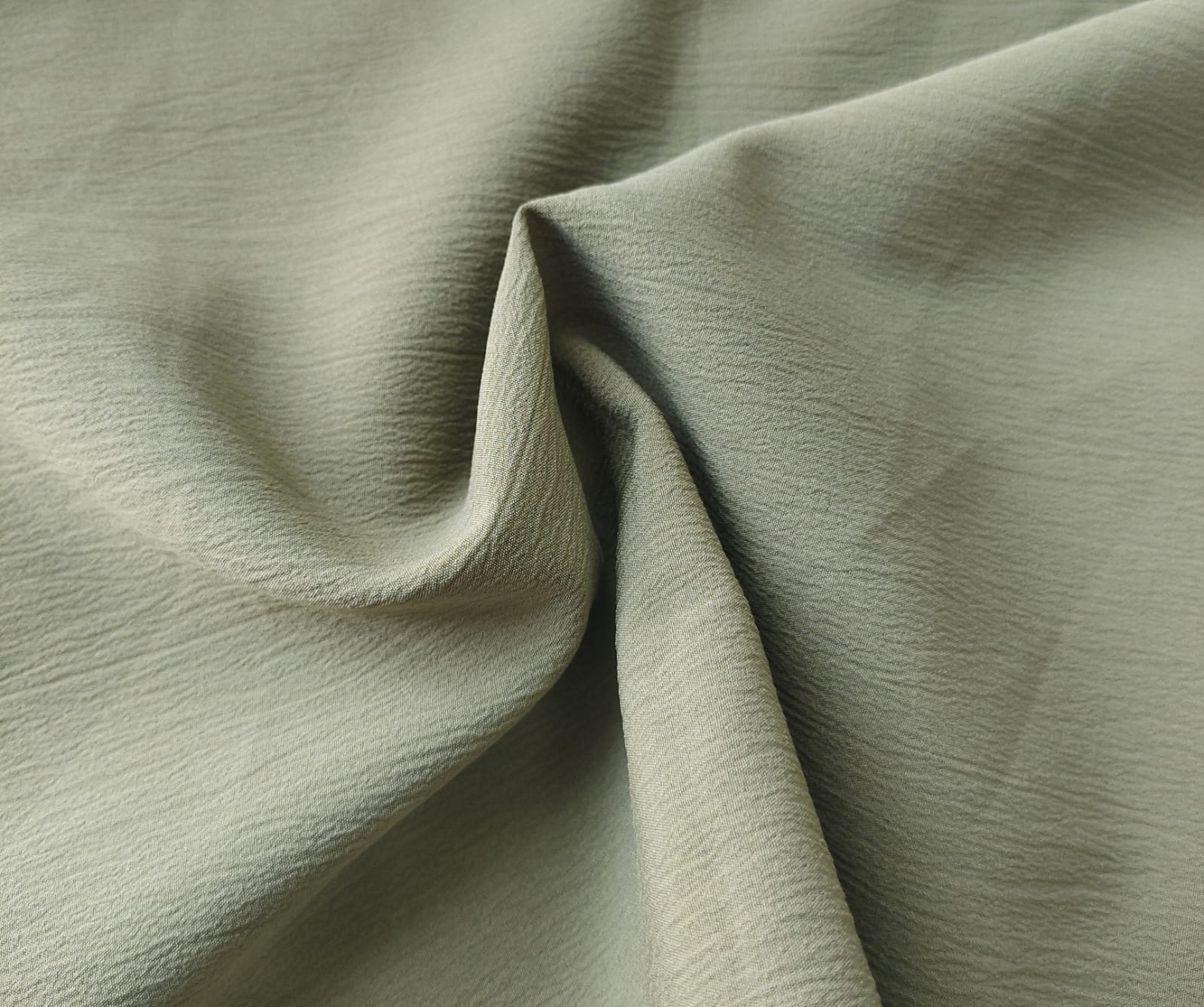 Close-up of soft, wrinkled pink cotton fabric displaying fine weave texture.