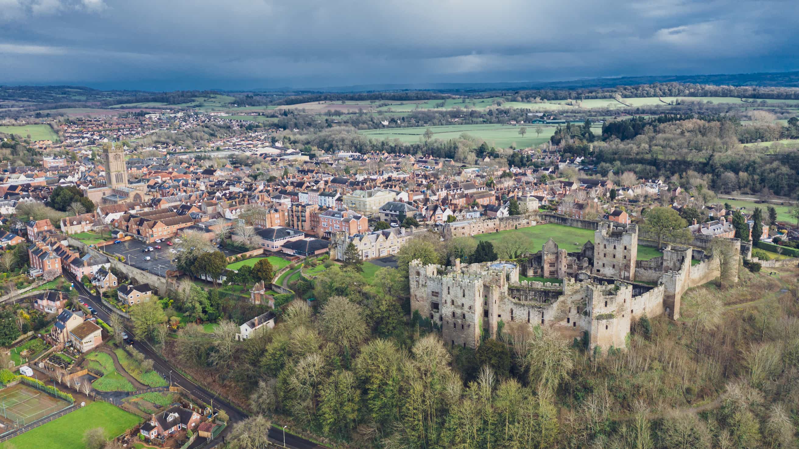 Aerial view of medieval castle ruins overlooking a historic English town and countryside
