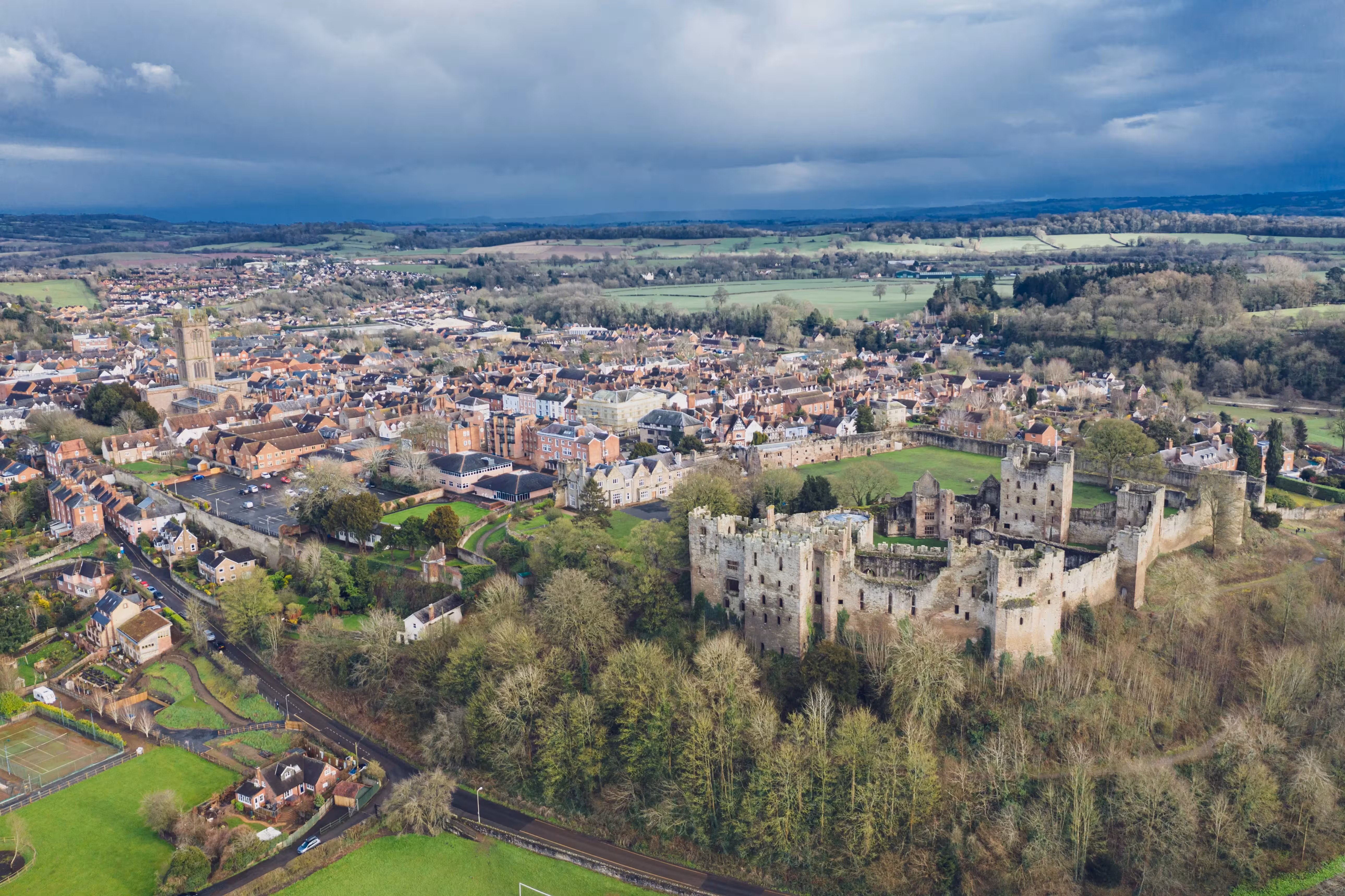 Aerial view of medieval castle ruins overlooking a historic English town and countryside