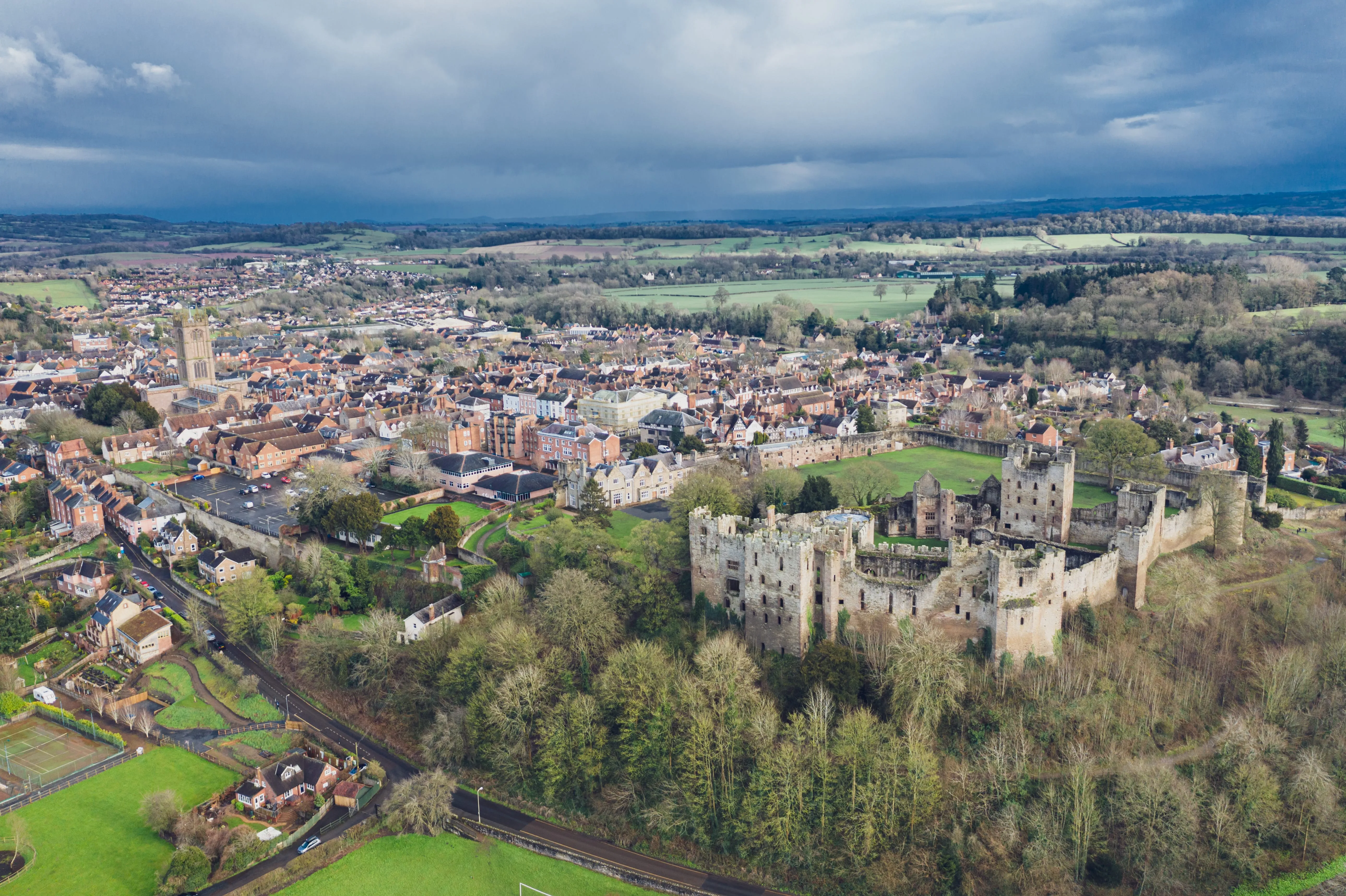 Aerial view of medieval castle ruins overlooking a historic English town and countryside