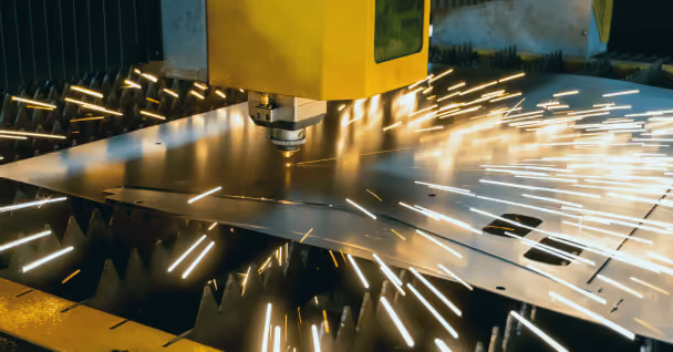 Yellow CNC machine cutting metal sheet with bright sparks flying around.
