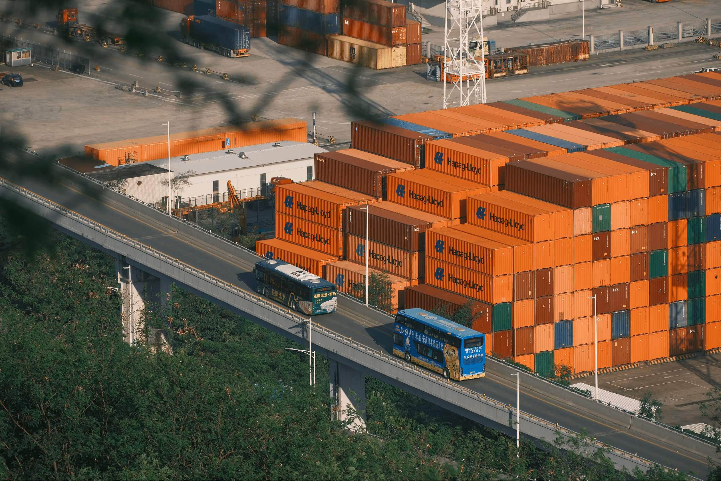 Aerial view of a large container terminal with rows of shipping containers and loading cranes.