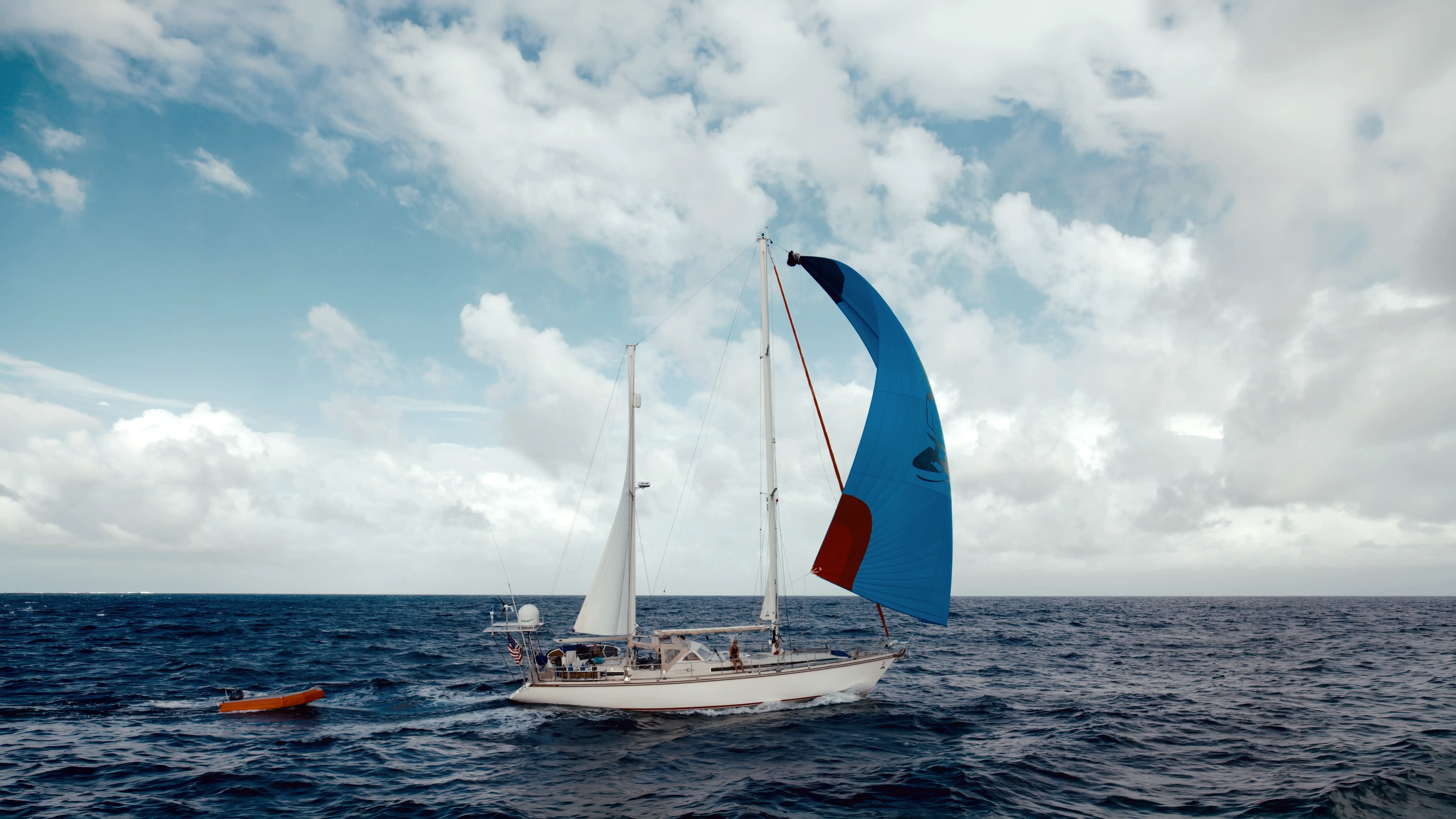 SV Delos sailing under a blue spinnaker in open water