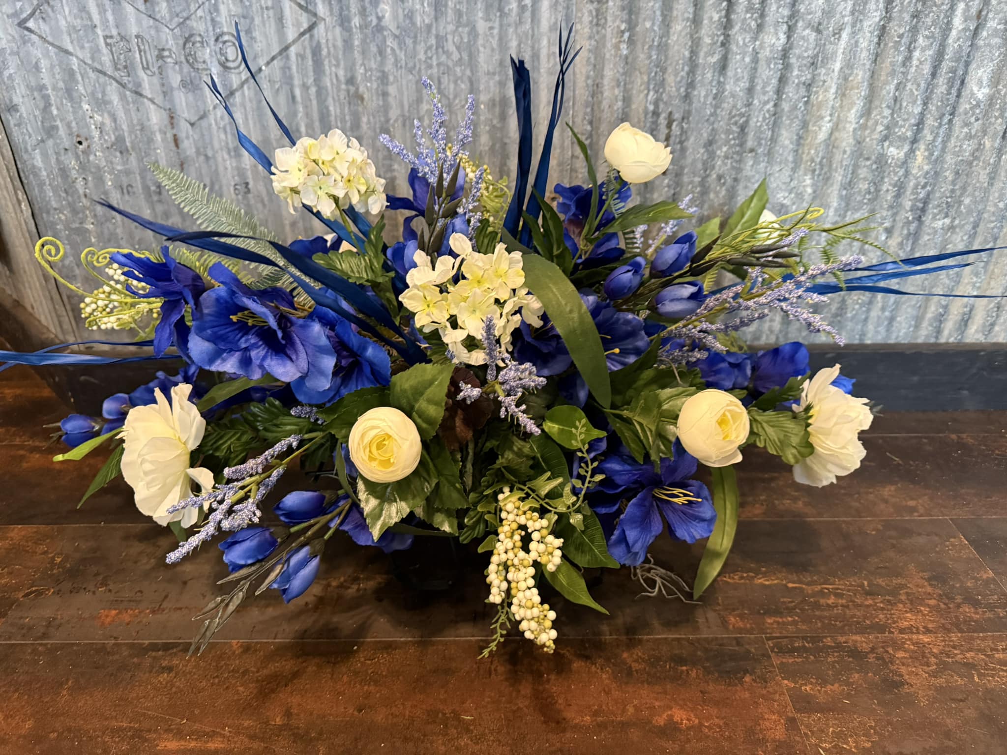 A blue and white sympathy arrangement with roses and delphinium by Simply Blooming
