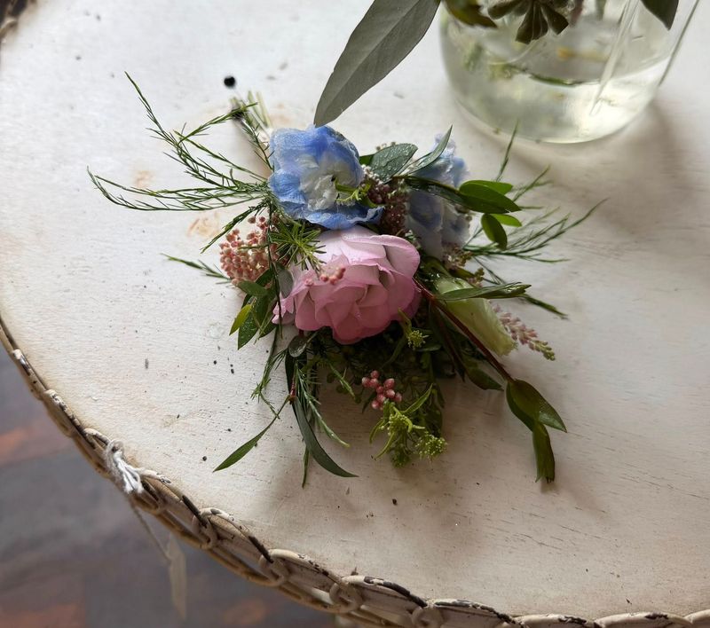 Pink rose boutonniere resting on a wood slice