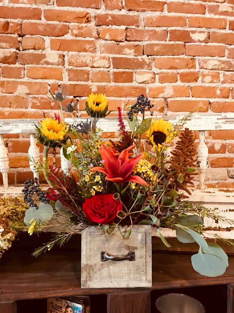 Fall centerpiece with red roses, sunflowers and eucalyptus