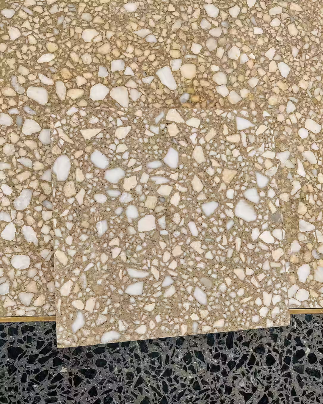 Overlapping terrazzo samples showing the original floor and a closely matched replacement mix