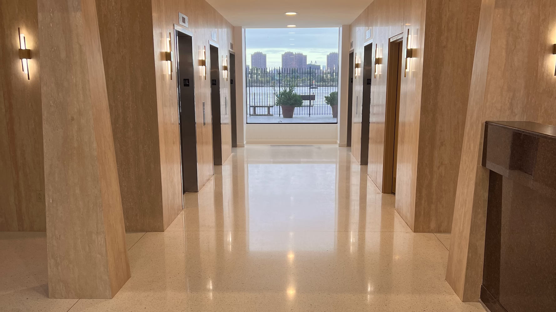 Custom epoxy terrazzo flooring and travertine walls in the Shore Towers elevator lobby in Astoria, New York.