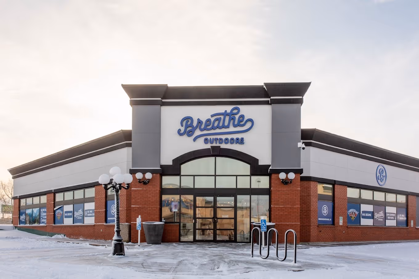 Front of Breathe Outdoors store building with snow-covered parking lot and lamp post.