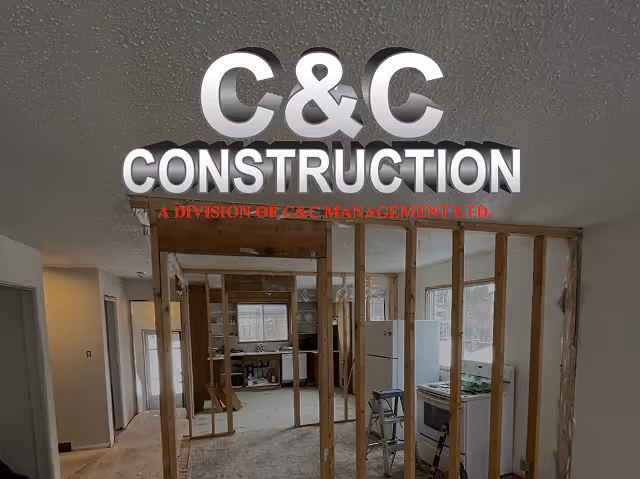 Indoor construction site with exposed wooden studs and a kitchen area in the background.
