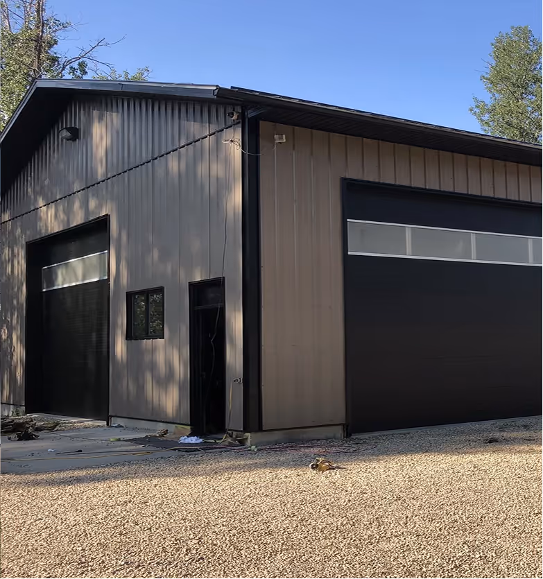 A modern metal building with two large black garage doors, painted by C&C Painting in Beaumont