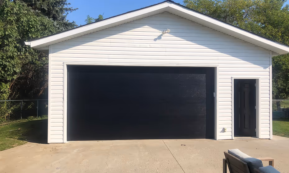 White garage with closed black overhead door and a side entry door, painted by C&C Painting in Sherwood Park