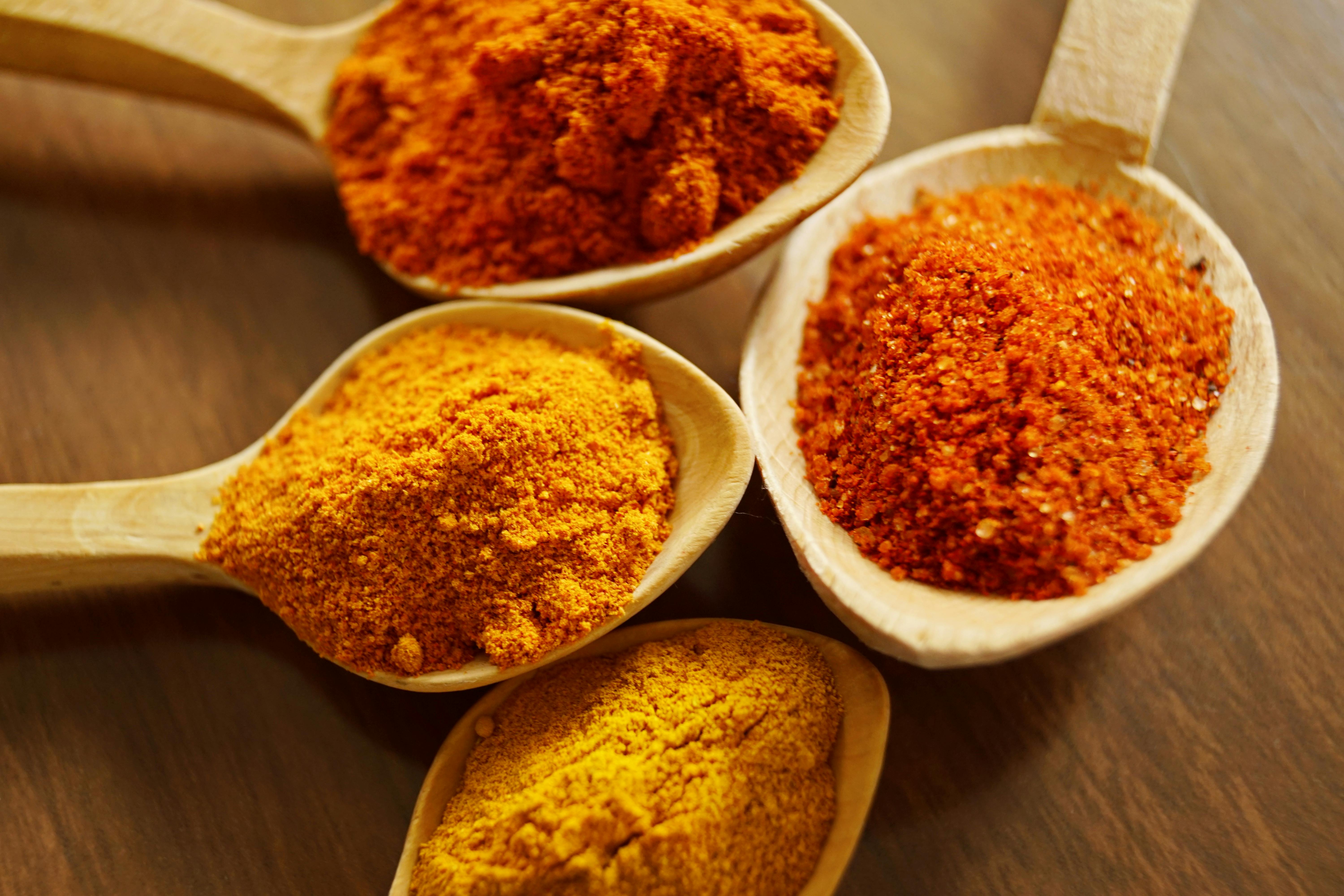 Indian spices including turmeric on wooden spoons