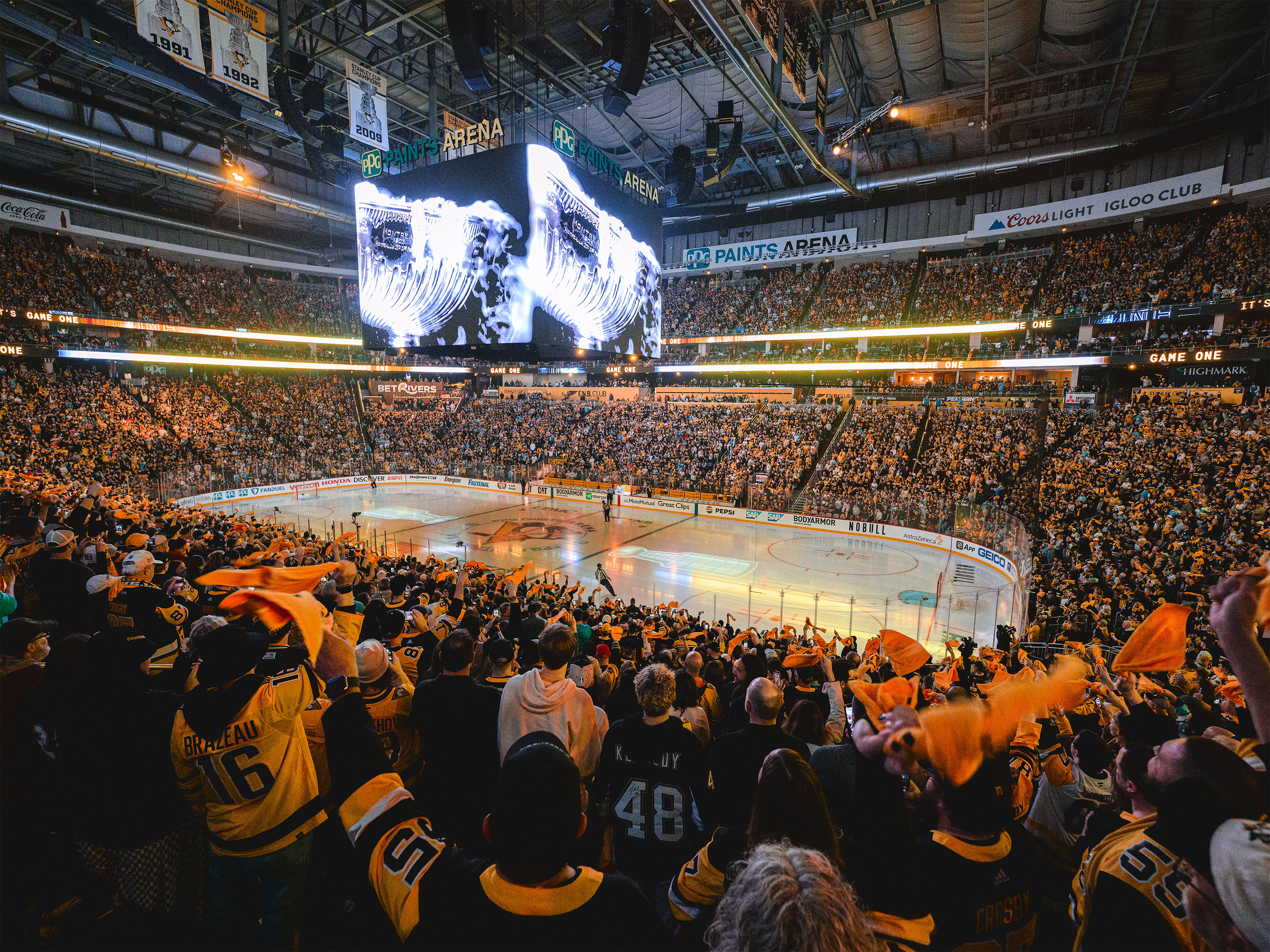 A wide angle shot of the inside of PPG Paints Arena with the Centering in the middle and fans waving gold towels.