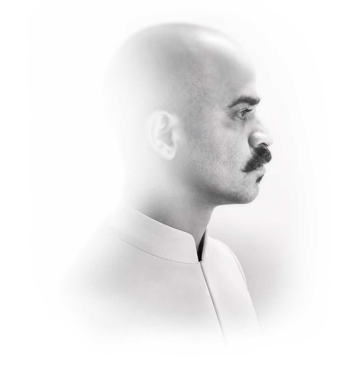 Black and white profile of a bald man with a mustache wearing a high-collared shirt.