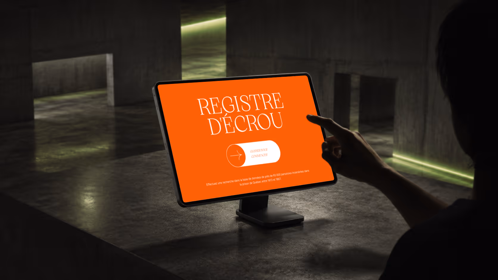 Person pointing at a tablet screen displaying a bright orange page titled Registre d'Écrou.