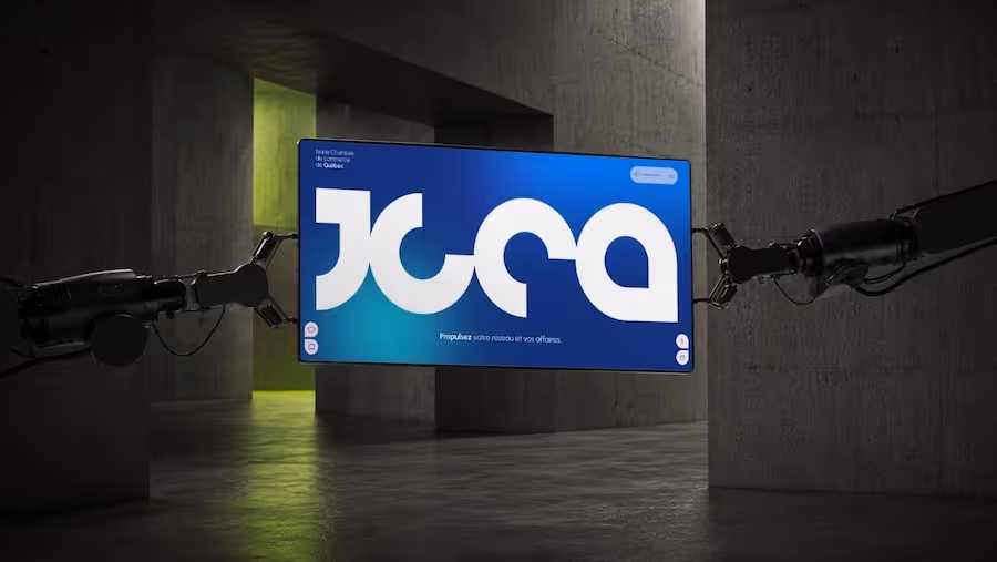 Robotic arms holding a screen displaying JCCA logo in a dim industrial space with concrete walls.