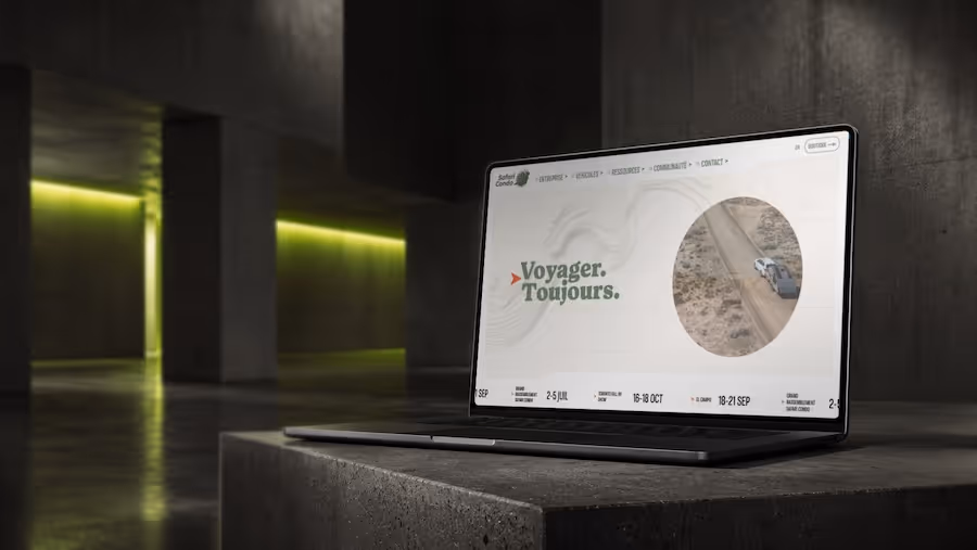 Laptop showing a travel website with text 'Voyager. Toujours.' and an image of a car on a dirt road.