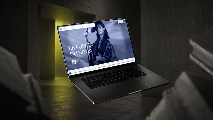 Laptop floating in dark room showing website with a woman and text 'LA FORCE DU NOUS'.