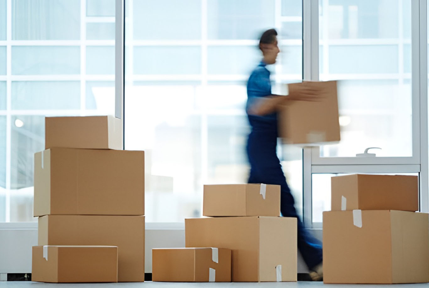 XMOVERS professional moving boxes being efficiently loaded during office relocation in modern high-rise building with floor-to-ceiling windows