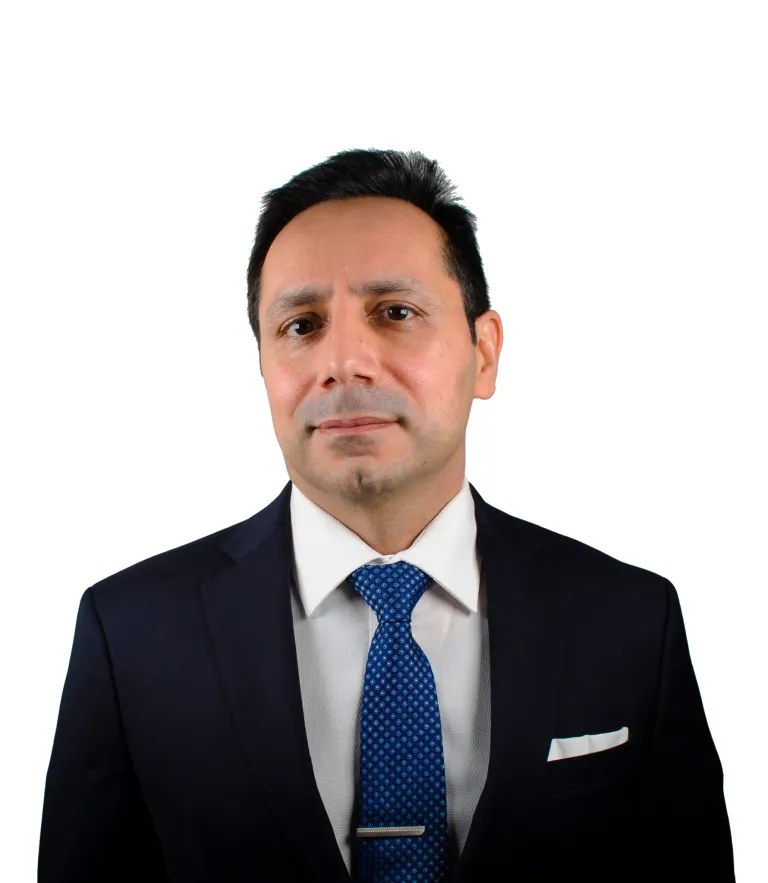 Man with dark hair wearing a navy suit, white shirt, and blue patterned tie against white background.